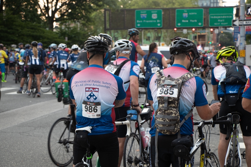 Riders gather at the starting line, on the back of the cycle shirt it states: Division of Public Safety, It's All About Relationships.