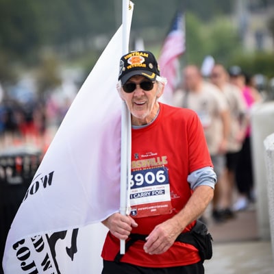 photo of veteran during 5k holding a flag