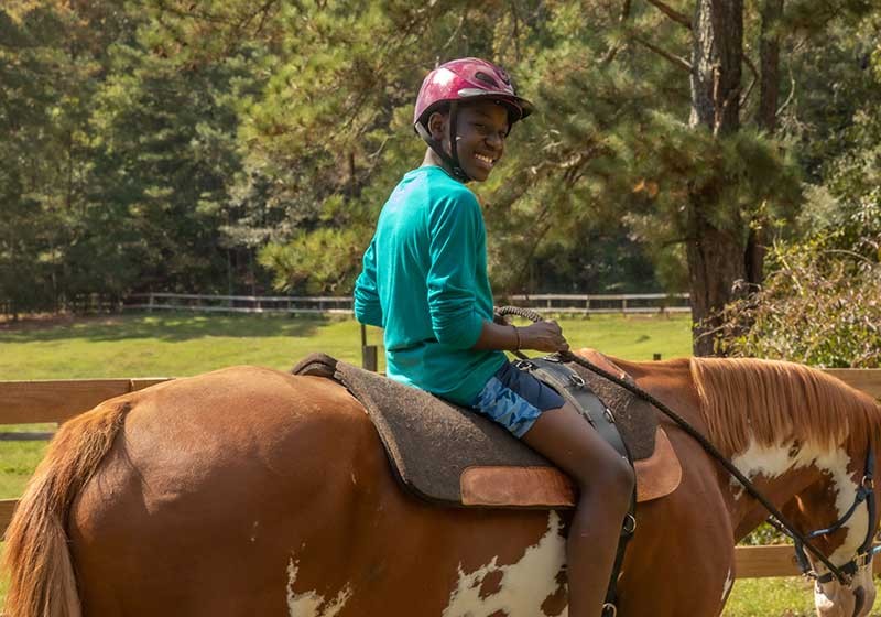 Youth riding on horse looking back smiling